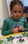 Аня показывает другим детям, как делать розочки из пластилина/Anja opettaa ruusujen tekemistä.